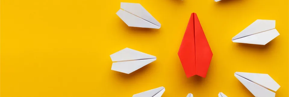 Roter Papierflieger zwischen weißen Papierfliegern